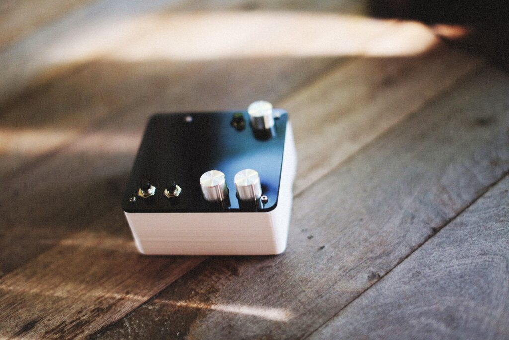 Close-up of electronic device with knobs on rustic wooden floor, showcasing a vintage aesthetic.